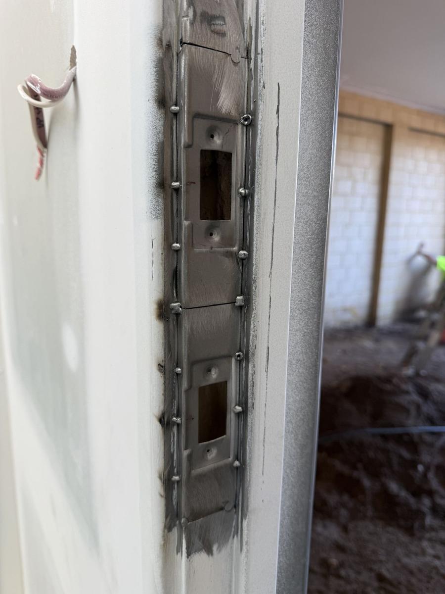 Steel frame jamb cut out and welded with new striker plates, weld still unground