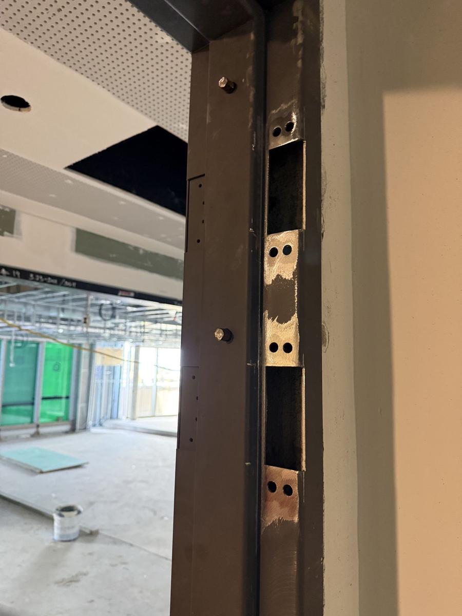 Commercial steel door frame with welded strike cut-outs on a fit-out site