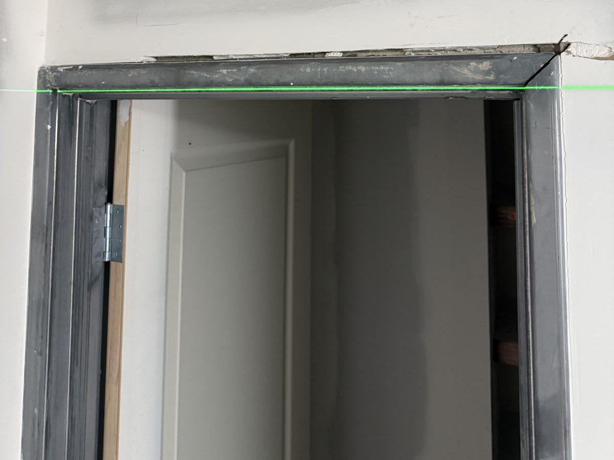 Raw steel door frame head with a gap above it